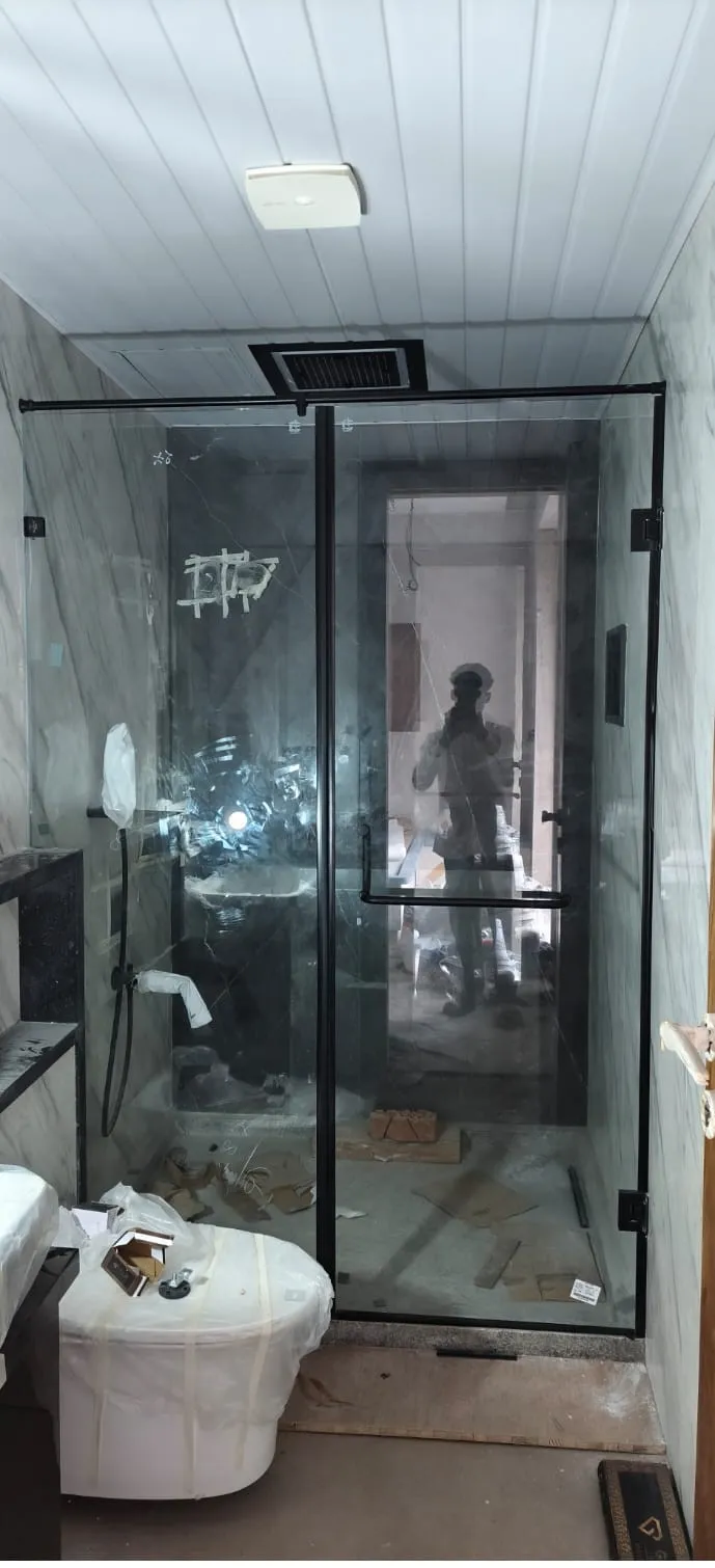 Contemporary walk-in glass shower enclosure with a bold black grid frame and clear tempered glass for a luxury industrial-style bathroom.