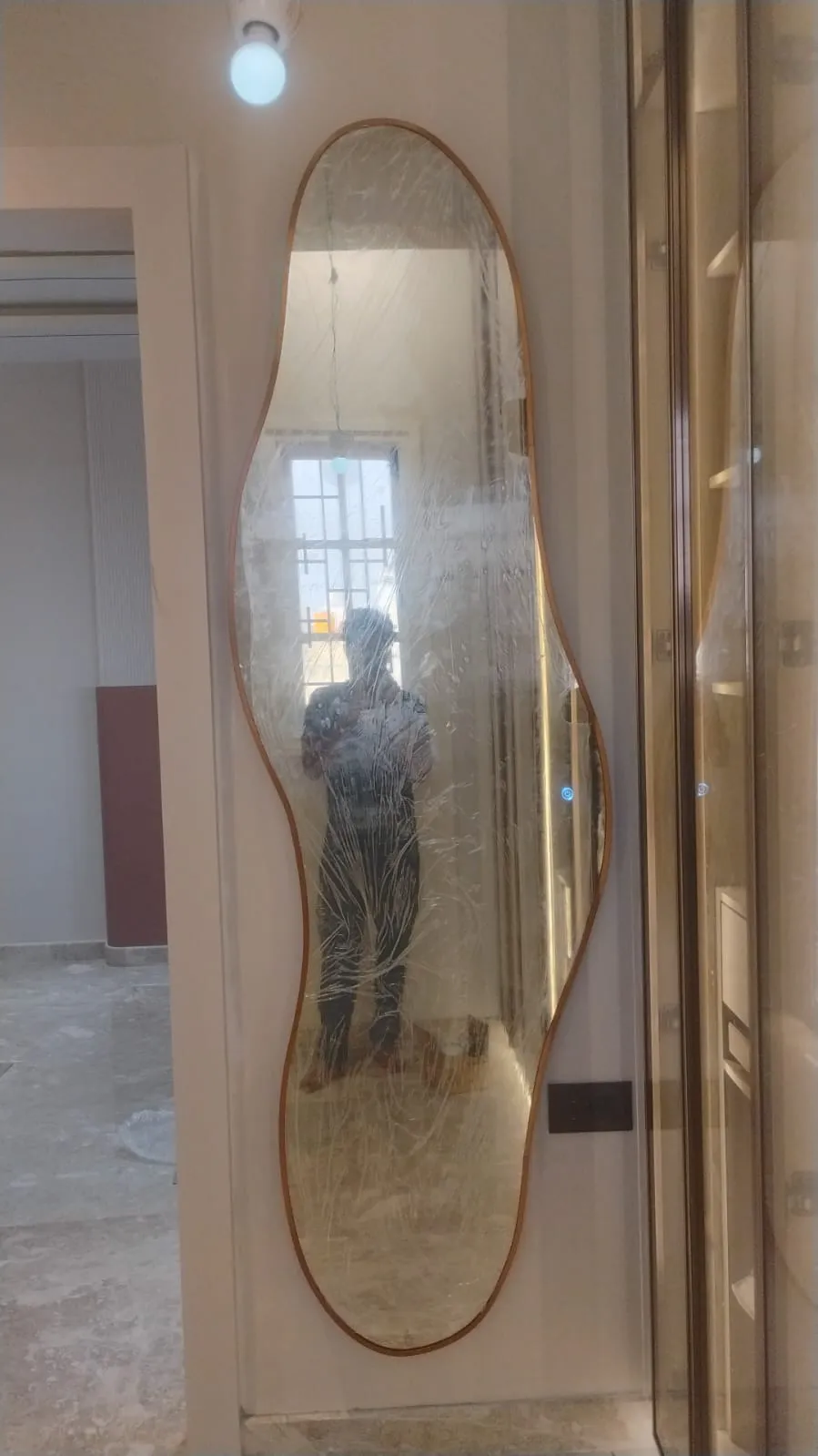 Modern decorative wall mirror with a unique curved wavy wooden frame, perfect for contemporary interior home or office decor.