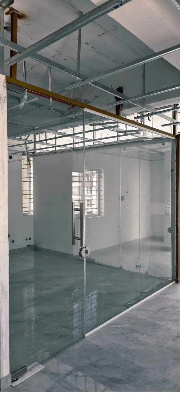 Contemporary glass pivot door at the office entrance of Fashion Elite, featuring an oversized floor-to-ceiling glass panel and premium hardware.