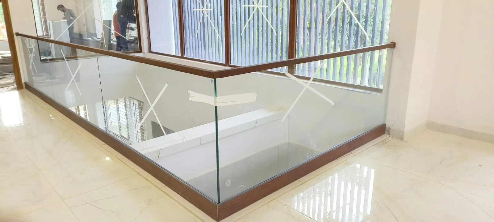 Modern interior glass railings with a polished wooden frame and handrail, featuring a sleek safety-first design for a contemporary staircase.