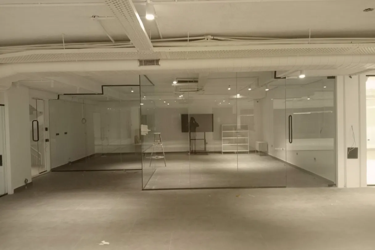 Minimalist floor-to-ceiling glass wall partition for a modern showroom, creating a seamless and transparent display space at Fashion Elite.