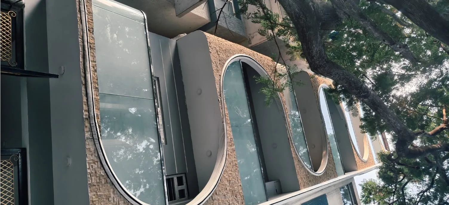 Modern architectural exterior featuring a large curved glass facade with seamless panels and sleek metal supports at the Fashion Elite building.